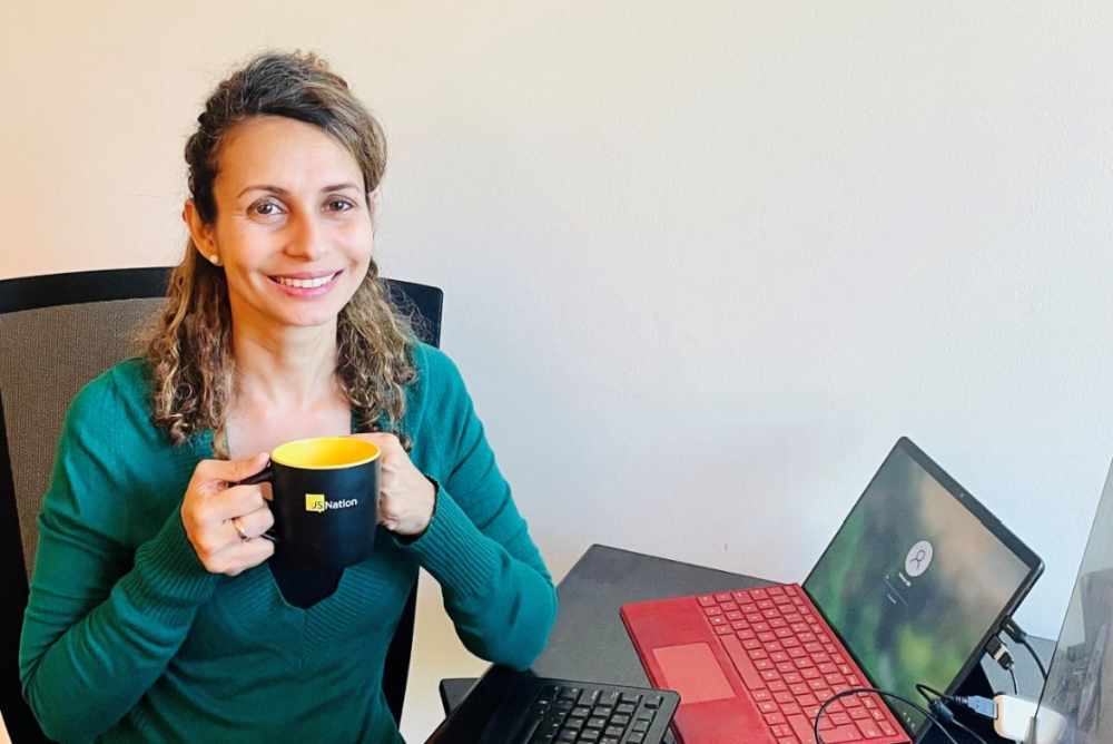 Vinnie holding a coffee cup sitting at desk with computer